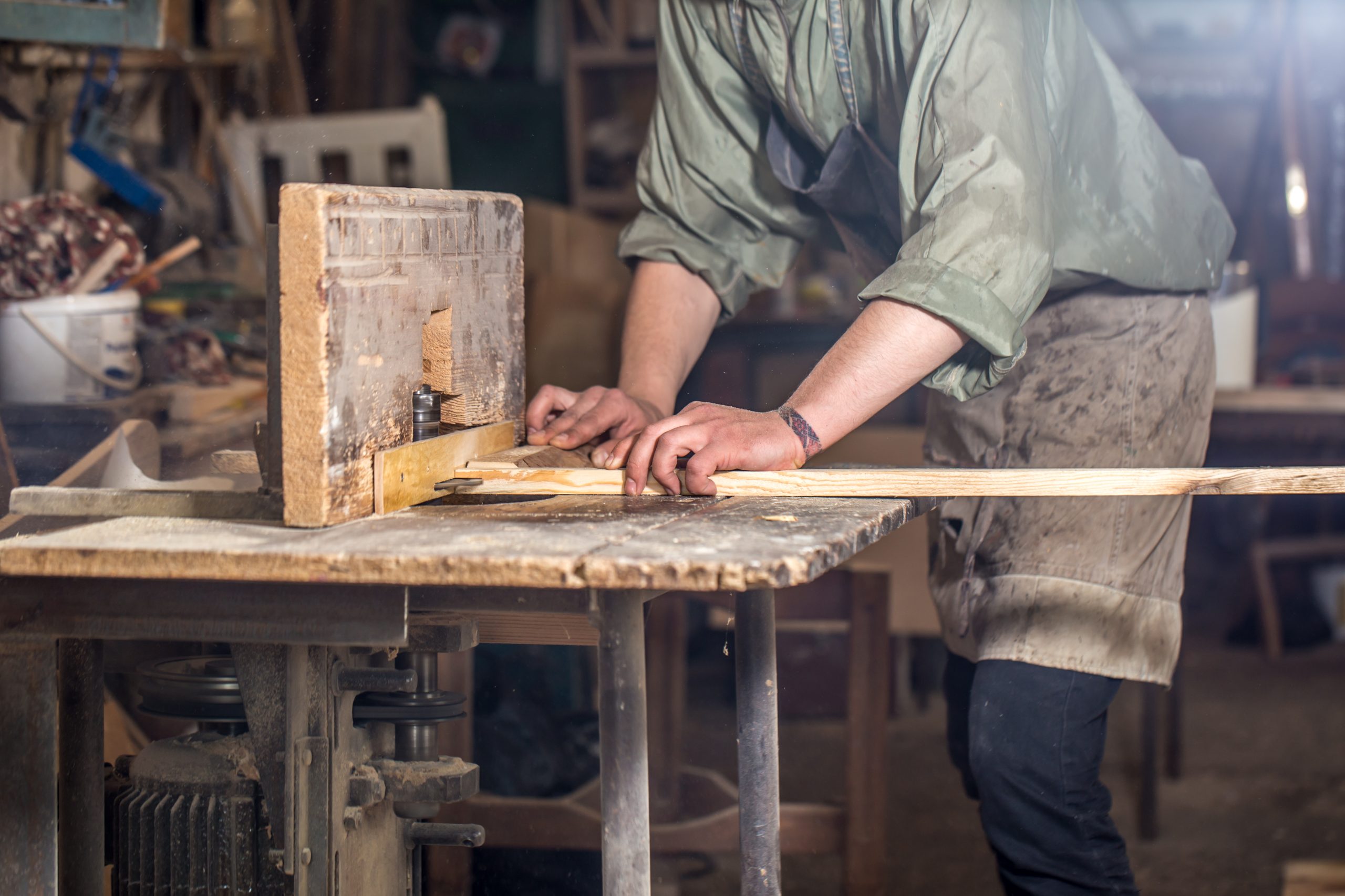 Carpenter working a length of timber at a workbench in a workshop